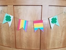 St. Patrick's Day Banner featuring two green and white panels with shamrocks and two rainbow panels hanging from a piece of string.