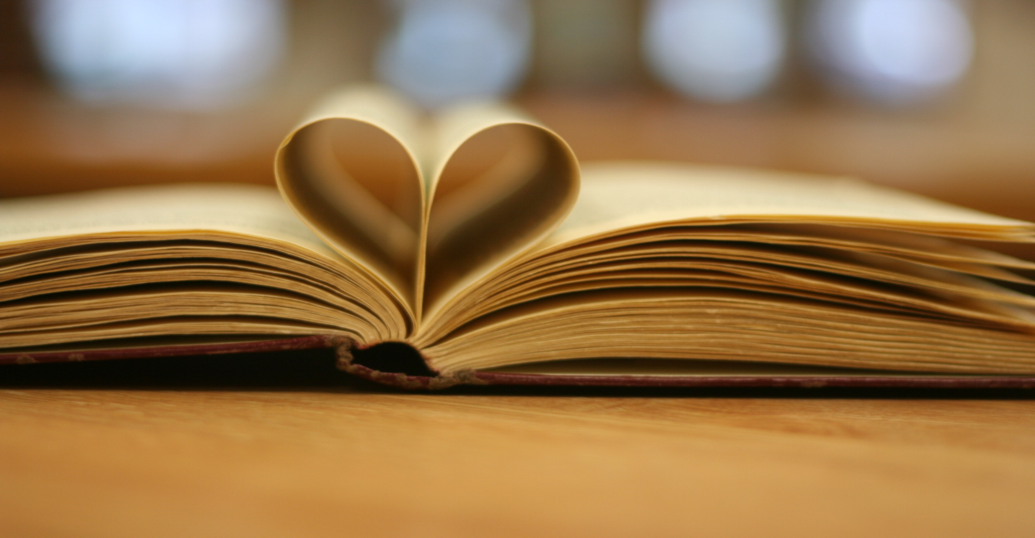 A book lying open with its center pages folded into the center to form a heart shape.